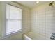 Simple bathroom with white tiled walls, tub, and window at 613 Mclean St, Spring Hope, NC 27882