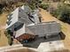 Aerial view of a gray-roofed house featuring solar panels and a spacious driveway, surrounded by lush greenery at 6336 Wrenwood Ave, Raleigh, NC 27607