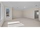 A carpeted empty room with multiple windows, natural light, neutral colors, and base molding at 6336 Wrenwood Ave, Raleigh, NC 27607