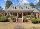 Charming brick home featuring a welcoming front porch, dormer windows, and professionally landscaped yard at 6336 Wrenwood Ave, Raleigh, NC 27607