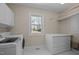 Well-lit laundry room featuring a front load washer and dryer, storage, and a window providing natural light at 6336 Wrenwood Ave, Raleigh, NC 27607