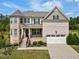 Charming two-story home featuring a stone and brick facade, a two-car garage, and lush landscaping at 701 Prince Dr, Holly Springs, NC 27540