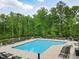 Community pool with lounge chairs and umbrellas surrounded by forest at 701 Prince Dr, Holly Springs, NC 27540