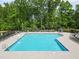 Community pool with lounge chairs and umbrellas surrounded by forest at 701 Prince Dr, Holly Springs, NC 27540