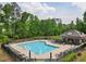 Large community pool with lounge chairs, umbrellas, and surrounding landscaping at 701 Prince Dr, Holly Springs, NC 27540