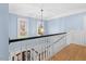 Upstairs hallway with hardwood floors, light blue walls, white trim, and a decorative chandelier at 705 Glen Eden Dr, Raleigh, NC 27612