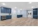 Open-concept basement area with blue cabinets and wet bar, complemented by sleek wood flooring and recessed lighting at 705 Glen Eden Dr, Raleigh, NC 27612