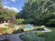 Lush landscaping surrounds backyard pool featuring stone accents, an inviting outdoor lounge area, and a walkway at 705 Glen Eden Dr, Raleigh, NC 27612
