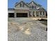 New two-story home featuring stone accents, a covered front porch, and an attached three-car garage at 72 Cultivator Ct, Angier, NC 27501