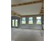 Open living room with multiple windows, French doors leading to the backyard, and unfinished ceiling beams at 72 Cultivator Ct, Angier, NC 27501