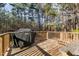 Outdoor deck with a wooden railing, grill covered, picnic table, and wooded landscape in background at 749 Fred Royster Rd, Henderson, NC 27537