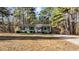 Charming single-story home with a metal roof nestled among mature trees and a sprawling front yard at 749 Fred Royster Rd, Henderson, NC 27537