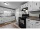 Well-lit kitchen featuring white cabinets and black appliances, providing a clean and functional space at 749 Fred Royster Rd, Henderson, NC 27537