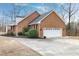 Side exterior of a brick home showing the garage, manicured bushes, and a large driveway at 8724 Ten Ten Rd, Raleigh, NC 27603