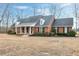 Brick home with a gabled roof and black shutters is surrounded by trees and a grassy yard at 8724 Ten Ten Rd, Raleigh, NC 27603