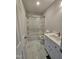 Well-lit bathroom features a sleek vanity, glass-enclosed tub with shower, and elegant marble-patterned tile flooring at 912 Hillsboro St, Oxford, NC 27565
