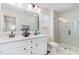 Modern bathroom with double vanity, sleek fixtures, large mirror, and a tiled walk-in shower at 94 Paperwhite Pl, Clayton, NC 27527
