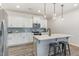 Bright kitchen with white cabinets, stainless appliances, an island with stools, and hardwood floors at 94 Paperwhite Pl, Clayton, NC 27527