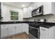 This kitchen boasts stainless steel appliances, white cabinets, and sleek black countertops, blending style and functionality at 1006 Linwood Ave, Durham, NC 27701