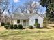 Charming one-story home with a gray roof, white siding and lush green landscaping at 1111 Spring Valley Lake Rd, Henderson, NC 27537