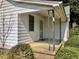 A covered front porch with concrete flooring and decorative wrought iron supports at 1111 Spring Valley Lake Rd, Henderson, NC 27537