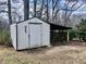 The metal shed offers sheltered storage space and an open wood storage area at 1111 Spring Valley Lake Rd, Henderson, NC 27537