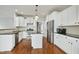 Bright kitchen features white cabinetry, stainless steel appliances, dark countertops and a center island at 1112 Jewel Creek Dr, Cary, NC 27519