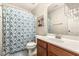 Well-lit bathroom with patterned shower curtain, warm wood cabinets, and neutral wall colors at 201 Timber Meadow Lk, Fuquay Varina, NC 27526