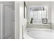Bright bathroom features a large soaking tub with tile surround and frosted glass window at 201 Timber Meadow Lk, Fuquay Varina, NC 27526