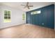 Bright bedroom with blue accent wall, two large windows, hardwood floor, and ceiling fan at 215 Purslane Dr, Franklinton, NC 27525