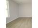 Bright living room featuring light gray walls, hardwood floors, and a large window showcasing the outdoor scenery at 2454 Englemann Dr # 380, New Hill, NC 27562