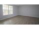 Bright living room featuring light gray walls, hardwood floors, and a large window showcasing the outdoor scenery at 2454 Englemann Dr # 380, New Hill, NC 27562