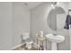 Cozy half bathroom featuring a pedestal sink, a round mirror, modern fixtures, and light gray wall paint at 3100 Cynthiana Ct, Raleigh, NC 27610