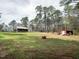 Expansive backyard with mature trees, a fire pit, red storage shed, and view of the home at 3130 State Hwy 58, Louisburg, NC 27549