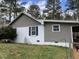 Side exterior showcasing white brick and gray wood siding with a window and black shutters at 3130 State Hwy 58, Louisburg, NC 27549