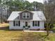 Charming home featuring a metal roof, white brick, black shutters, and tasteful landscaping at 3130 State Hwy 58, Louisburg, NC 27549