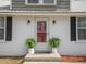 Welcoming front entrance with a storm door, brick facade, potted ferns, and updated lighting fixtures at 3130 State Hwy 58, Louisburg, NC 27549