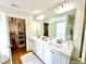Bathroom featuring double sinks, white cabinetry, a large mirror, updated lighting and a large walk-in closet at 897 W Main St, Benson, NC 27504
