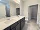 Bathroom with dual sinks, gray cabinets, large mirror, and tiled shower at 1794 Parham Dr, Graham, NC 27253