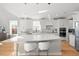 Spacious white kitchen with a large central island, modern pendant lighting, and white counter stools at 204 Woodstaff Ave, Wake Forest, NC 27587