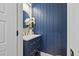 Stylish powder room with blue paneled accent wall and a decorative mirror over a single vanity at 204 Woodstaff Ave, Wake Forest, NC 27587