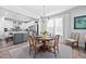 Open-concept dining area with a wood table, chandelier, and a view into the modern kitchen at 2109 Flycatcher Ln, Fuquay Varina, NC 27526