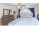 Bedroom includes a bed with blue bedding, a dresser with a mirror, and natural light from the windows at 234 Palmetto Tree Way, Knightdale, NC 27545