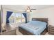 A bedroom featuring a bed with blue bedding, large windows, and a ceiling fan at 234 Palmetto Tree Way, Knightdale, NC 27545