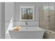 Luxurious bathroom with freestanding tub, large window, and glass-enclosed shower at 290 Whistlers Cv, Louisburg, NC 27549