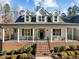 Inviting front porch with brick base, black railings, and ample seating space, perfect for relaxing outdoors at 290 Whistlers Cv, Louisburg, NC 27549
