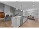 Open-concept kitchen with island seating and stainless steel appliances flows into the living area with fireplace at 290 Whistlers Cv, Louisburg, NC 27549