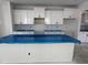Spacious kitchen featuring an island covered in blue plastic and white cabinets with black hardware at 316 White Oak Garden Way # 217, Garner, NC 27529