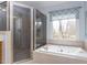 Luxurious bathroom featuring a jetted tub, a glass-enclosed shower, and neutral tile throughout at 3359 Hampton Rd, Raleigh, NC 27607
