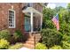 Close-up of the brick home's front porch with blue door, showcasing the American flag and manicured landscaping at 3359 Hampton Rd, Raleigh, NC 27607
